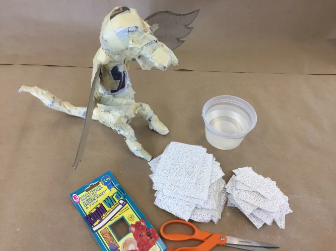 The third step of creating a dragon with Rigid Wrap plaster cloth is to cut Rigid Wrap into smaller pieces.